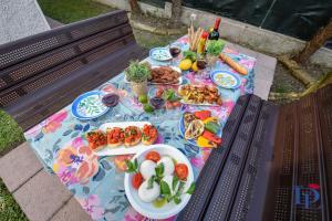 una mesa de picnic con platos de comida en un banco en DesenzanoLoft Villa Palm Garda Beach, with garden, barbecue and pool, en Desenzano del Garda