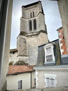 a church with a tall tower on top of a building at Gîte les jasmins centre historique Saint-Astier in Saint-Astier
