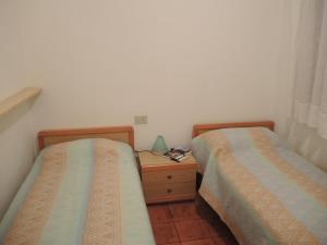 duas camas num pequeno quarto com mesa de cabeceira em Villa Katiò em Bibione