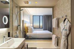 a bathroom with a tub and a sink and a bed at Pullman Paris Montparnasse in Paris