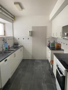 a kitchen with white cabinets and a tile floor at Sjømannskirken Narvik in Narvik