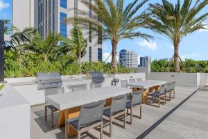 un patio con mesas, sillas y palmeras en Downtown Fort Lauderdale 1BR w WD Pool Gym MIA-12, en Fort Lauderdale