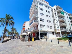 a large white building on the beach with palm trees at CalafellBeach.SeaViews,New in Calafell