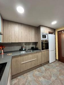a kitchen with wooden cabinets and a white refrigerator at Allotjament Sanuy a Tremp in Tremp