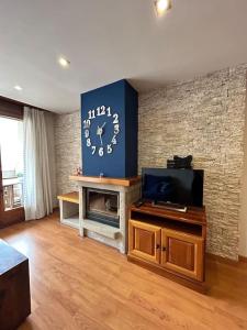 a living room with a tv and a clock on a wall at Allotjament Sanuy a Tremp in Tremp