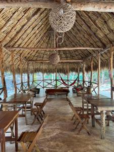 uma grande cabana de palha com mesas e cadeiras e um lustre em Hotel B. Secreto Maya em Yaxché