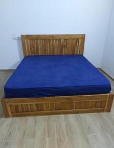 - un lit avec un matelas bleu et un cadre en bois dans l'établissement Villa Eloy, à Lomé