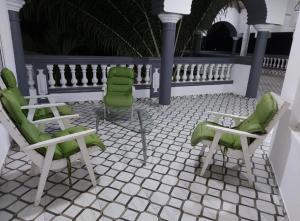 d'une terrasse avec 2 chaises vertes et une table. dans l'établissement Villa Eloy, à Lomé