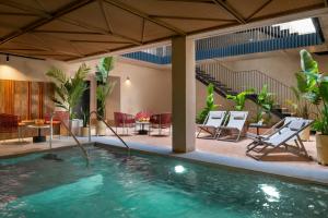 einen Pool in einem Haus mit Stühlen und einem Tisch in der Unterkunft Magno Apartments Castilla in Sevilla