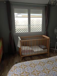 una culla in una camera da letto con finestra di Les coquelicots en Baie de Somme a Saint-Blimont