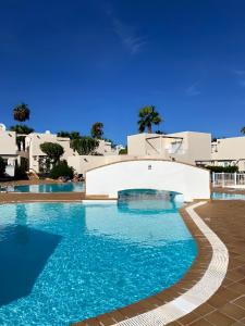 basen z błękitną wodą i białymi budynkami w obiekcie Red Hibiscus Corralejo iRent Fuerteventura w Corralejo