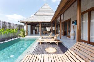 a house with a swimming pool and wooden benches at Kano Canggu in Canggu