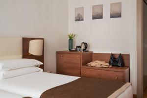 a bedroom with two beds and a wooden dresser at Palazzo Porta Romana Hotel in Milan