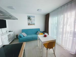 salon z niebieską kanapą i stołem w obiekcie Red Hibiscus Corralejo iRent Fuerteventura w Corralejo