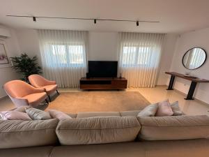 uma sala de estar com um sofá e uma televisão de ecrã plano em LUX House 15 min Fatima - Nazare em Leiria