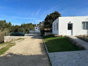 uma casa branca com um carro estacionado ao lado de uma entrada em LUX House 15 min Fatima - Nazare em Leiria