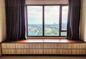 een stoel bij het raam met uitzicht op de stad bij Da Men Space for 2 by Concept A Suites near Sunway Subang in Subang Jaya
