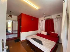 sypialnia z łóżkiem z czerwoną ścianą w obiekcie HANGOUT BEACH STAY w mieście Mahabalipuram
