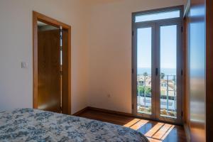 ein Schlafzimmer mit einem Bett und einem großen Fenster in der Unterkunft Tranquilidade in Estreito da Calheta
