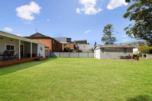 a backyard with a lawn and a house at Abode Callala Beach Jervis Bay - 100m to Beach! in Callala Beach
