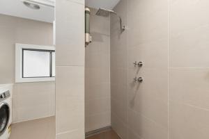 a bathroom with a shower and a washing machine at Abode Callala Beach Jervis Bay - 100m to Beach! in Callala Beach +26 photos