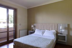 a bedroom with a bed with white pillows and a window at Tenuta Lamborghini Golf & Resort in Panicale