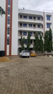 una macchina bianca parcheggiata di fronte a un grande edificio di Cozy Apartment - Nyali Mombasa a Mombasa