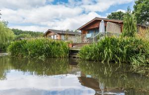 una casa en el río con su reflejo en el agua en Ivy Cabin with Hot Tub en York