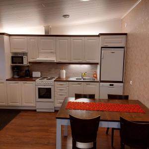 una cocina con armarios blancos y una mesa con sillas. en Mesijäinen, en Pyhäjärvi