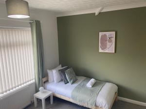 a bedroom with a bed in a green wall at Wilton - Perfect Home for Contractors Private Large Drive in Newcastle upon Tyne