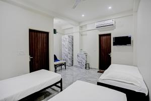 S B Guest House Near New Delhi Train Station في نيودلهي: غرفة فندقية بسريرين وتلفزيون