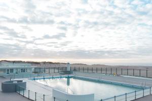 una piscina junto a una playa y un edificio en Oostduinkerke Res Henri IV, en Oostduinkerke