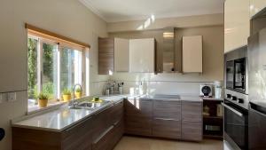 une cuisine avec des placards en bois et une grande fenêtre dans l'établissement Sunshine by Check-in Portugal, à Albufeira