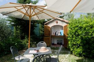 een tafel en stoelen met een parasol en een grill bij Il Melo in Castellina in Chianti