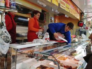 Een man die eten klaarmaakt in een supermarkt met mensen die er staan. bij Il Melo in Castellina in Chianti