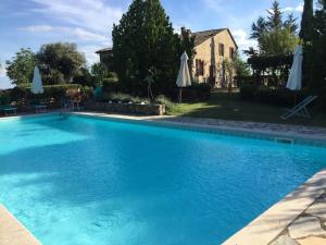 een groot blauw zwembad met parasols in een tuin bij Il Melo in Castellina in Chianti