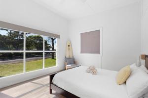 a bedroom with a bed and a large window at Abode Callala Beach Jervis Bay - 100m to Beach! in Callala Beach