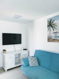 salon z niebieską kanapą i telewizorem w obiekcie Red Hibiscus Corralejo iRent Fuerteventura w Corralejo