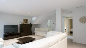 ein weißes Wohnzimmer mit einem weißen Sofa und einem TV in der Unterkunft Torrevieja Villa Azalea in Torrevieja