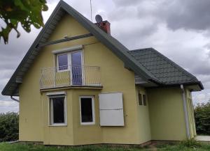 a yellow house with a balcony and a roof at Siedlisko Gródek Dwór 