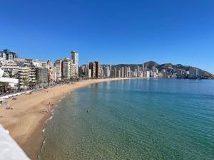 a beach with people in the water and buildings at Apartamento Familiar - Sunset Waves -Grupo AMI in Benidorm
