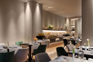 a restaurant with tables and chairs and a kitchen at Palazzo Porta Romana Hotel in Milan