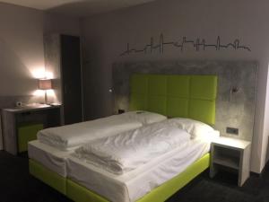 a bedroom with a bed with a green headboard at SleepySleepy Hotel Dillingen in Dillingen an der Donau