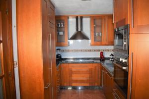 - une cuisine avec des placards en bois et un réfrigérateur noir dans l'établissement Casa Villa Mey, à Candás