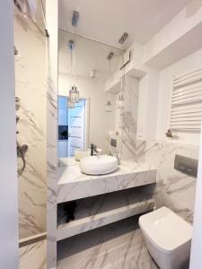biała łazienka z umywalką i toaletą w obiekcie Ice Apartments w Krakowie