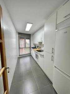 een keuken met witte kasten en een koelkast bij Apartamento en palmeira - Colores del Barbanza Naranja in Ribeira