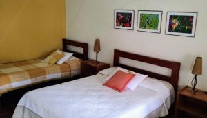 a bedroom with two beds and two lamps and pictures on the wall at Pousada Caminho da Serra in São Roque de Minas