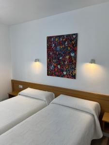 2 Betten in einem Zimmer mit Wandgemälde in der Unterkunft Pensión Zeus in Barakaldo
