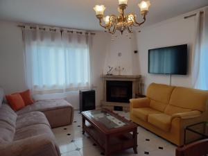 a living room with a couch and a chandelier at Acogedora casa de campo-PISO Y ATICO con finca- in Neda