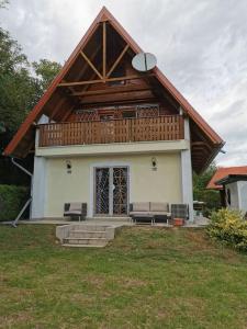 a house with a gambrel roof with a porch at Erdőszélén Házikó Vendégház in Kehidakustány